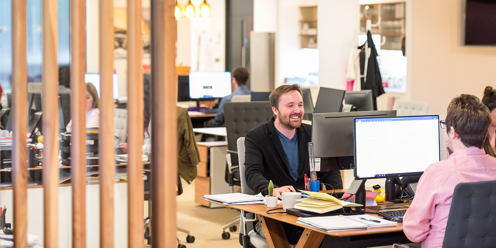 Smiling man sitting at desk and computer screen