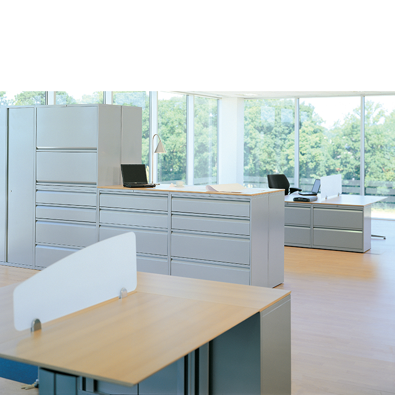 White storage units in an office setting with desks and laptops